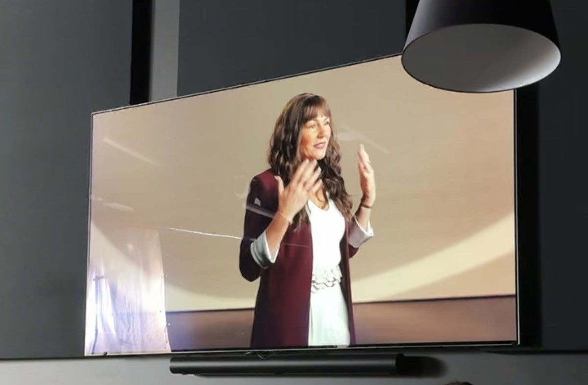 Audra Leigh speaking on stage, shown on a large screen